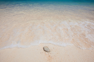 Wave of the sea on the sand beach and single stone