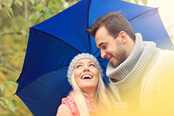 Young romantic couple with umbrella in the park in autumn