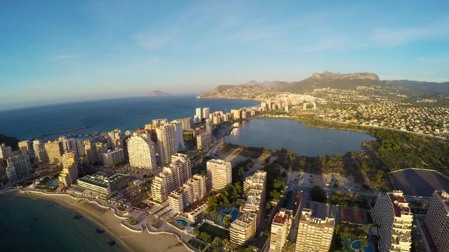 Aerial view of Calpe, Costa Blanca during the day. Popular summer resort in Spain with mediterranean sea and Las Salinas lake, mountains at the background, skyscrapers - hotels, apartments.