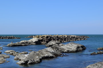 消波ブロック／山形県の庄内浜で撮影した、消波ブロックの写真です。消波ブロックは、海岸や河川などの護岸を目的に設置するコンクリートブロックです。海岸沿いに多数のブロックをかみ合わせて並べることで、波のエネルギーを減衰・消散させる事が可能です。また、このブロックにより、水中に複雑で多様な生物生息空間を提供し、円滑な生態系が形成され豊かな水域環境を創り出しています。