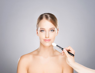 Beautiful girl is being applied with cosmetics.