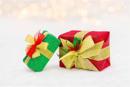 Red and green Christmas gift box with shiny golden ribbon. Bokeh with glow effect on white background