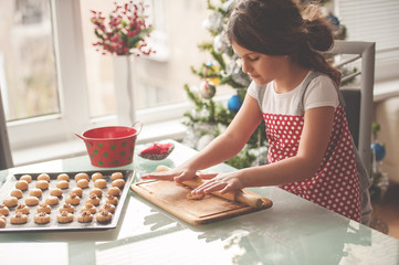 Beautiful little girl making homemade cookies for Christmas , Christmas atmosphere - obrazy, fototapety, plakaty