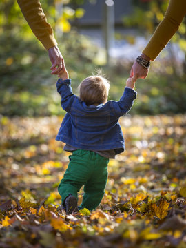 Kleinkind mit Eltern beim Spaziergang im Herbst