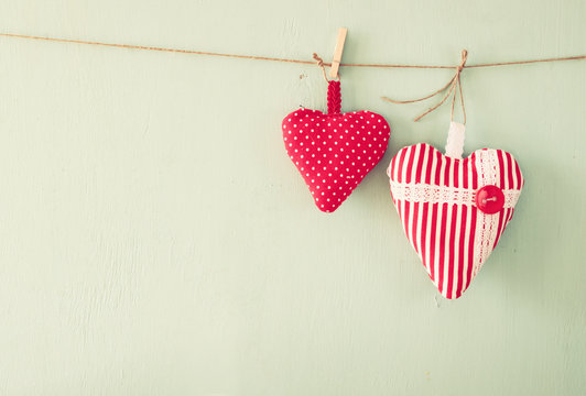 image of fabric hearts hanging on rope in front of wooden background. retro filtered
