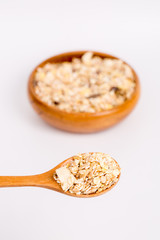 Muesli in bowl and wooden spoon on white background
