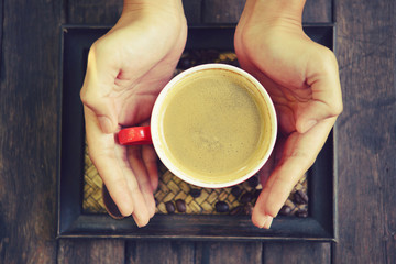 woman holding hot cup of coffee,on table wooden