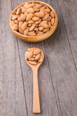 Almonds in wooden bowl on wooden