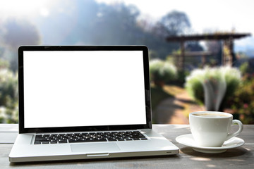 Laptop and coffee cup on wooden in the morning with garden backg