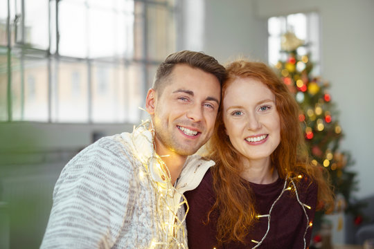 lachendes paar hat spaß an weihnachten und dekoriert sich mit lichterketten