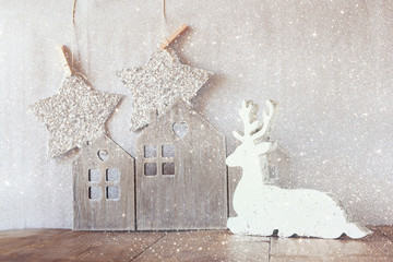 image of white wooden reindeer and glitter stars hanging on rope over glitter silver background