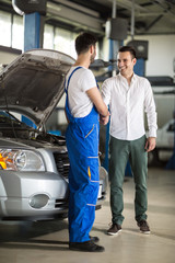 smiling auto mechanic and client shaking hands