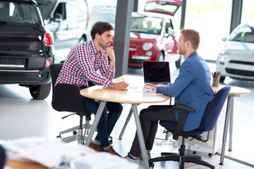 Young man talking with car dealer