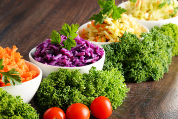 Composition with four vegetable salad bowls on wooden table