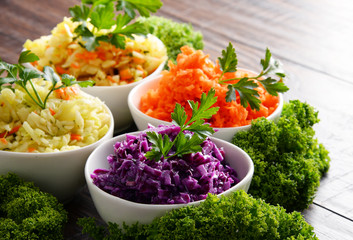 Composition with four vegetable salad bowls on wooden table