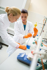 Two chemical technician place liquid with lab pipette