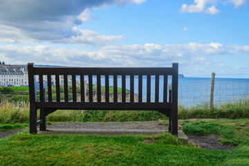 Fototapeta na wymiar Wooden bench with the look at blue sea and the horizon in Whitby Abbey, North Yorkshire, UK