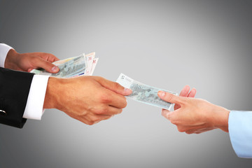 Woman hand takes money from the man's hand on grey background