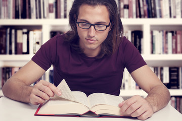 Young man reading book in library