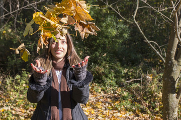 Young woman throwing yellow autumn leaves