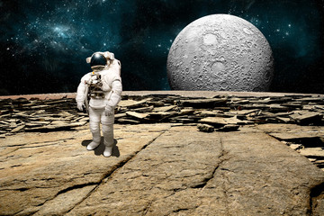 A stranded astronaut surveys his situation on a barren moon - Elements of this image furnished by NASA. - 94800413