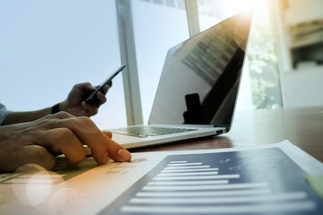 business man hand working on laptop computer with business graph