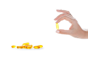 Soft gels pills with Omega-3 oil in fingers closeup on white