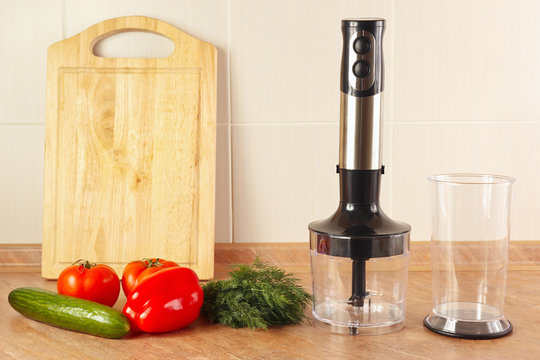 Fresh vegetables with herbs and a blender on the kitchen table