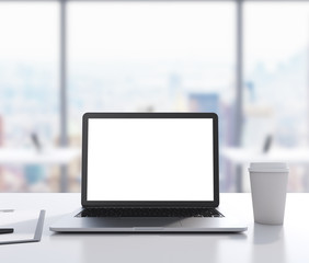 There are a laptop with white copy space screen, legal pad and a cup of coffee on the table. 3D rendering. Modern office with panoramic New York view in blur on the background.
