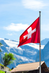 Swiss flag against Alps mountains