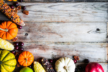 Pumpkins,corn,apples,nuts and cranberries on wooden background