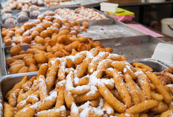 Heap of typical sweet italian rice crespelle covered with powdered sugar, for sale on the table of a street seller in Sicily