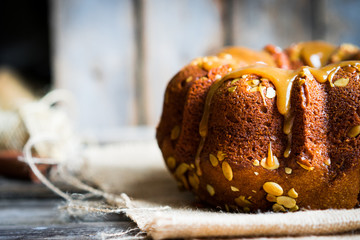 Homemade autumn cake with pumpkin seeds and caramel on wooden ba