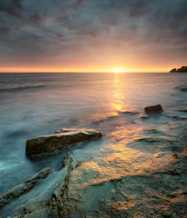 Rocks on sea shore during sunrise. Beautiful natural summer seascape