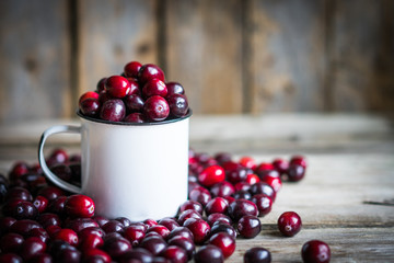 Cranberries on a mug on rustic wooden background