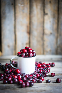 Cranberries on a mug on rustic wooden background