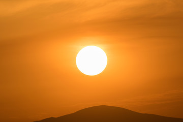 Close up of the sun against the mountains.
