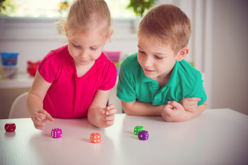 Two happy children playing with dices
