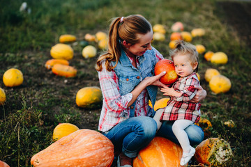 Fototapeta premium Mother and daughter sitting on pumpkins