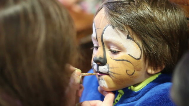 Little boy with painted face as a lion for a carnival