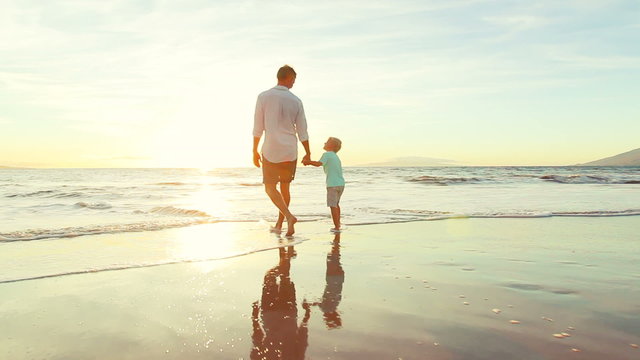 Father and Son Walking Holding Hands Together at the Beach at Sunset. Happy Fun Smiling Lifestyle.