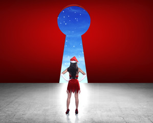 Woman wearing santa claus costume looking big key hole