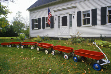 Row of Red wagons in yard with American Flag