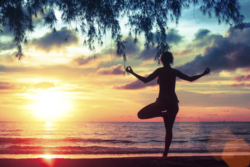 Yoga and healthy lifestyle. Silhouette meditation girl on the background of the sea and sunset.