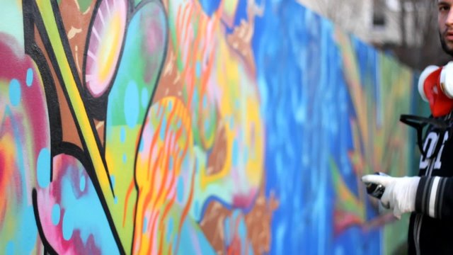 Hip Hop Rap artist with a beard and mask Teenager make graffiti on the wall