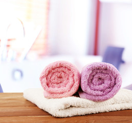 Obraz na płótnie Canvas Rolled bath towels on wooden table in bathroom