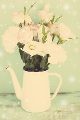 Beautiful eustoma flowers in teapot, on color background