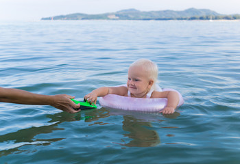 Happy smiling baby girl swimming in the sea. Thailand, Phuket, BangTao beach