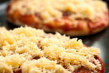 Mini pizzas or small pellets covered with cheese close-up macro