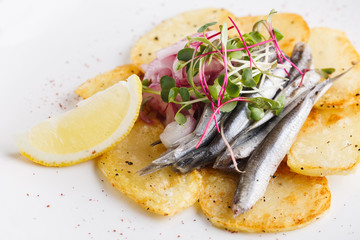 Anchovies with potatoes and vegetables on a plate